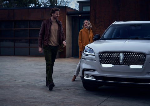 A man and a woman approaching a 2024 Lincoln Aviator® SUV, which illuminates certain lights when they are close | Maguire's Lincoln in Palmyra PA