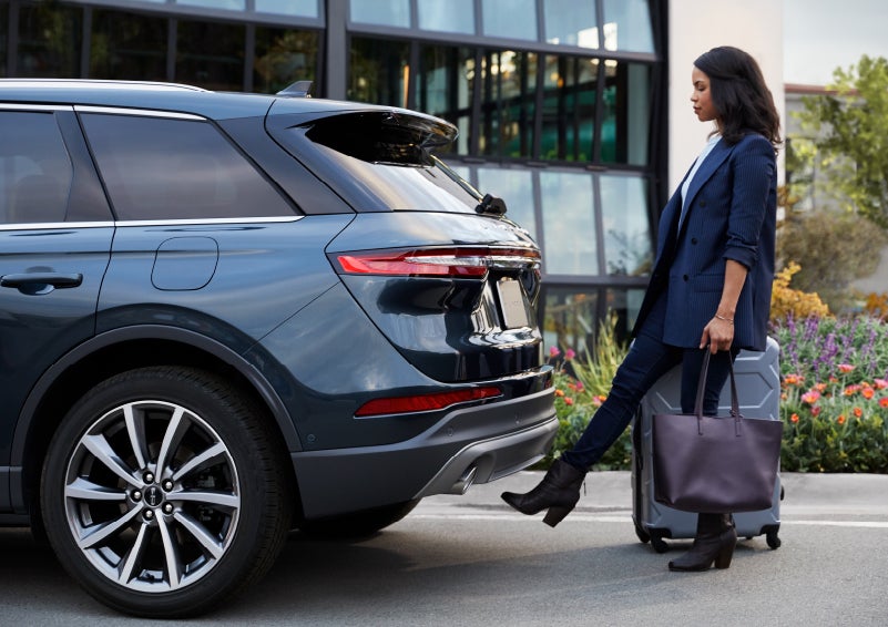 A woman with luggage and a bag opens the available hands-free liftgate by kicking her foot under the bumper | Maguire's Lincoln in Palmyra PA