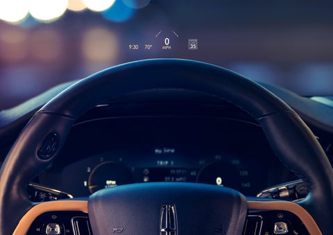 The available head-up display projects data on the windshield above the steering wheel inside a 2022 Lincoln Corsair as the driver navigates the city at night | Maguire's Lincoln in Palmyra PA